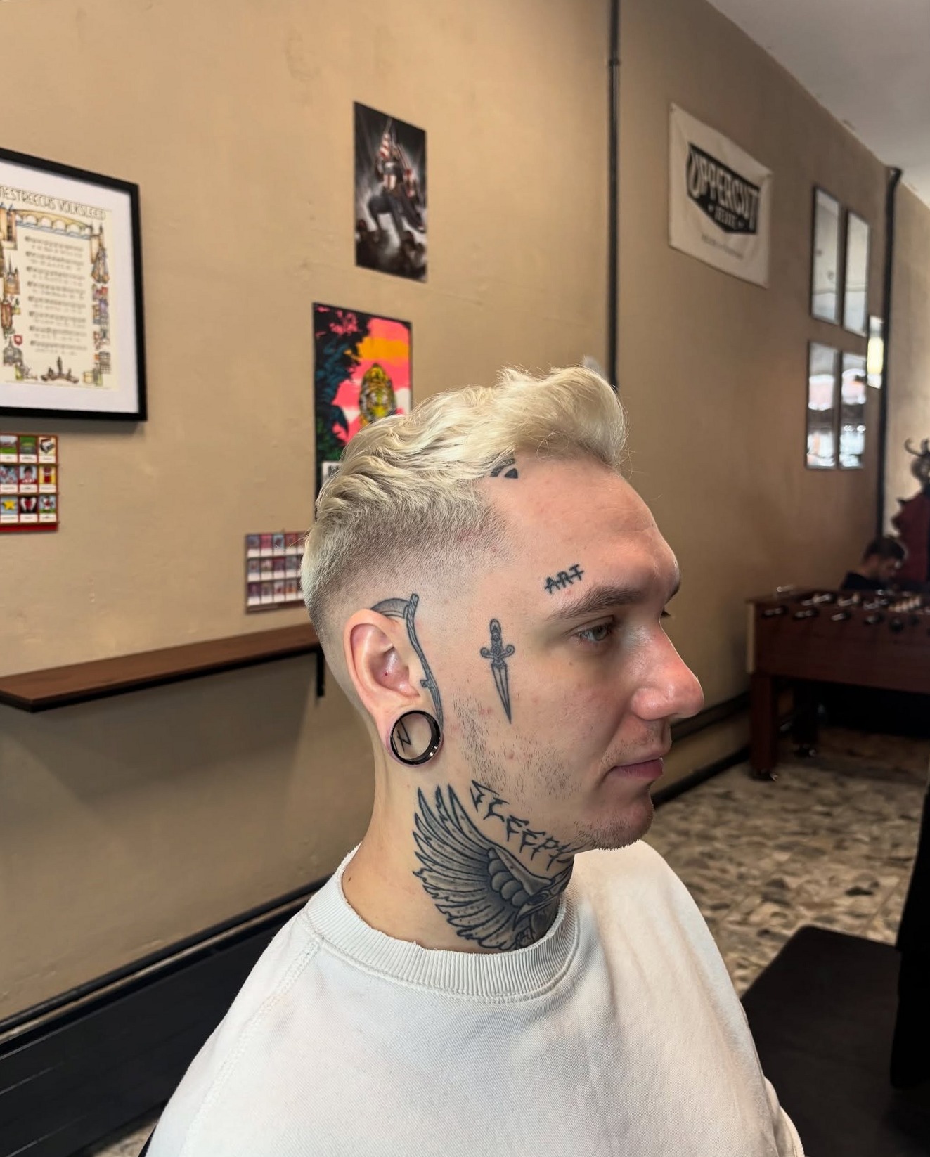 Klant met een fade en platinablond haar bovenop, van opzij in de shop